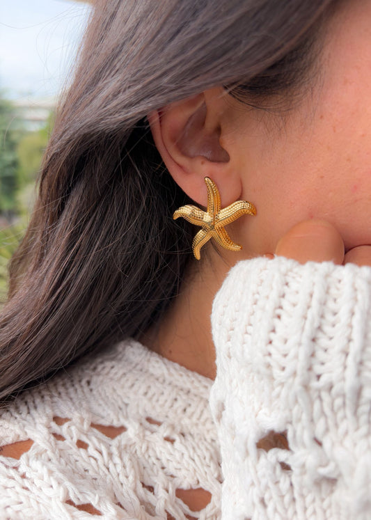 Boucles d’oreilles étoile de mer dorées portées avec crochet, look estival léger